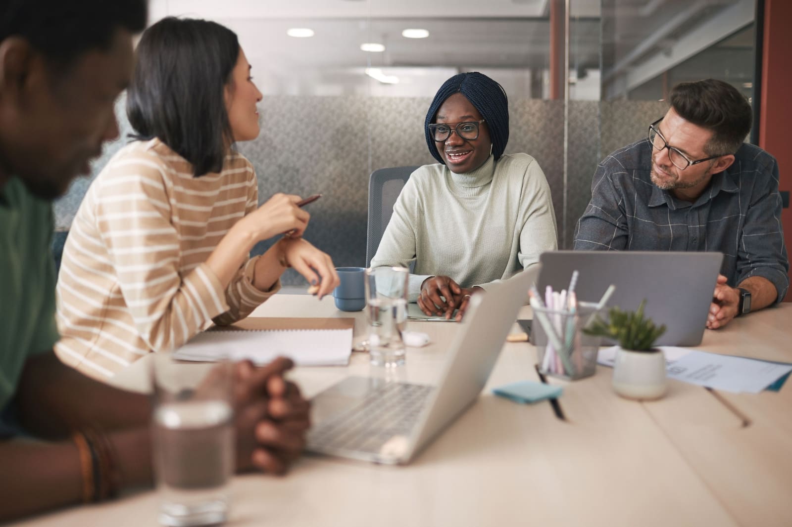 A group talking around a meeting table with laptops.